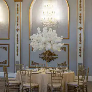 Elegant event decor with gold accents and a luxurious floral centerpiece.