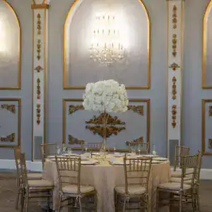 Elegant banquet table with gold chairs and luxurious floral centerpiece at upscale event space.