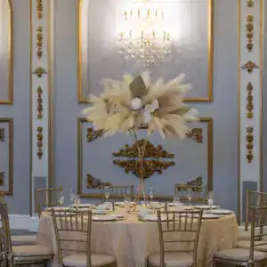 Elegant event table setup with sophisticated gold accents and a tall floral centerpiece.
