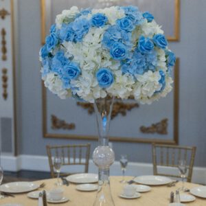 Elegant floral centerpiece for wedding or event decoration featuring blue and white hydrangeas and roses.
