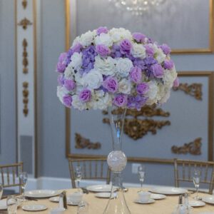 Elegant floral centerpiece for wedding or event decor made with white, purple, and lavender roses.