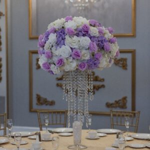 Elegant floral centerpiece with purple and white roses at a luxury event table.